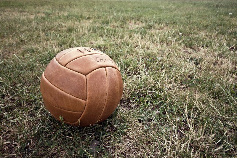 Ein historischer Lederfußball, der auf einer Wiese liegt